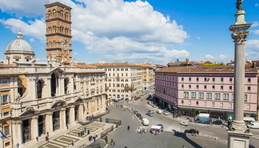Piazza animata con la maestosa basilica di Santa Maria Maggiore a Roma, torre campanaria e colonna antica.