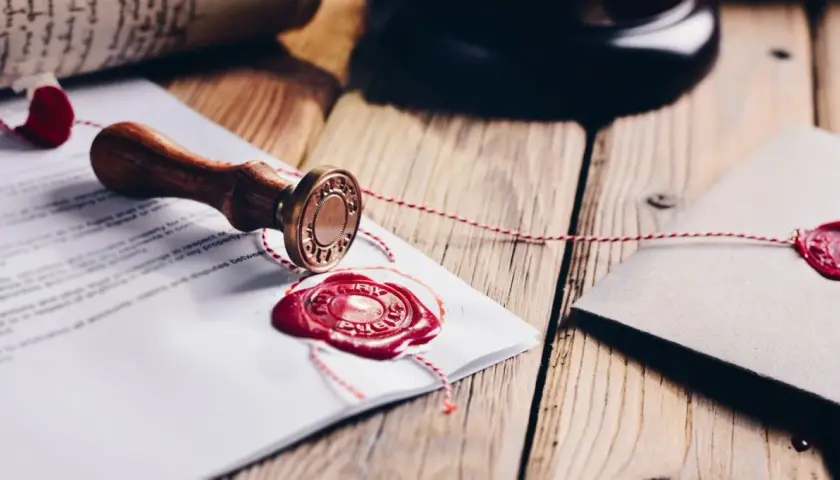 Pieczęć notarialna i dokumenty z czerwonym woskiem, symbolizujące rozporządzenie taksa notarialna.