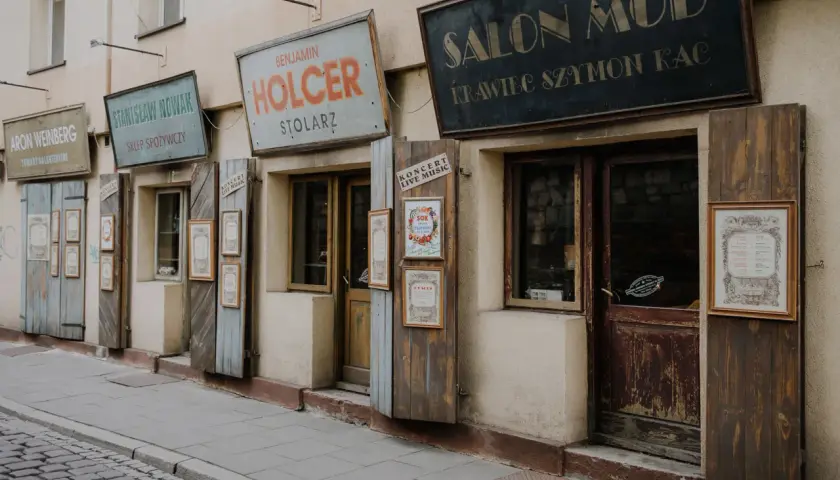 Stare szyldy sklepów w krakowskim quartiere ebraico: "Salon Mód", "Holcer Stolaz", "Stanisław Nowak Sklep Spożywczy".