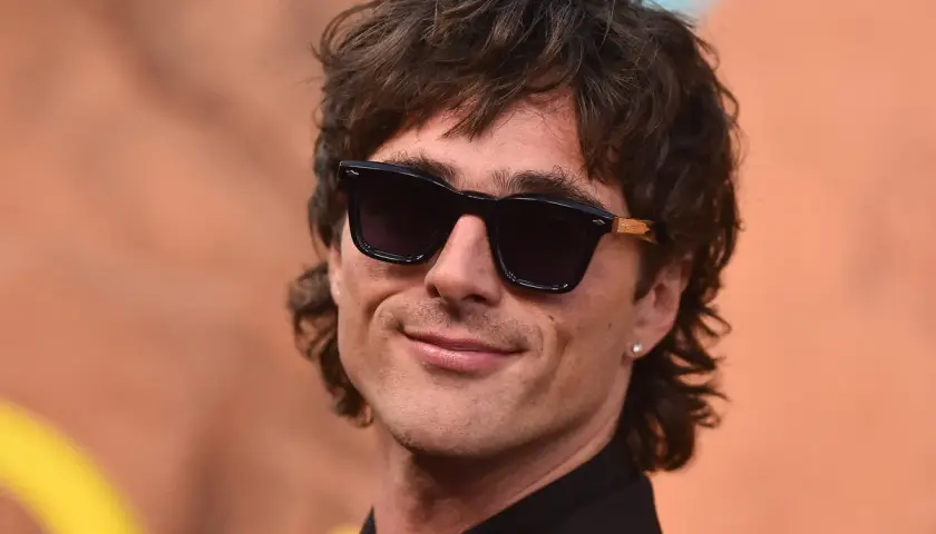 Hombre con corte de pelo moderno, gafas de sol oscuras y sonrisa. Un estilo que anticipa el corte de pelo hombre 2026.