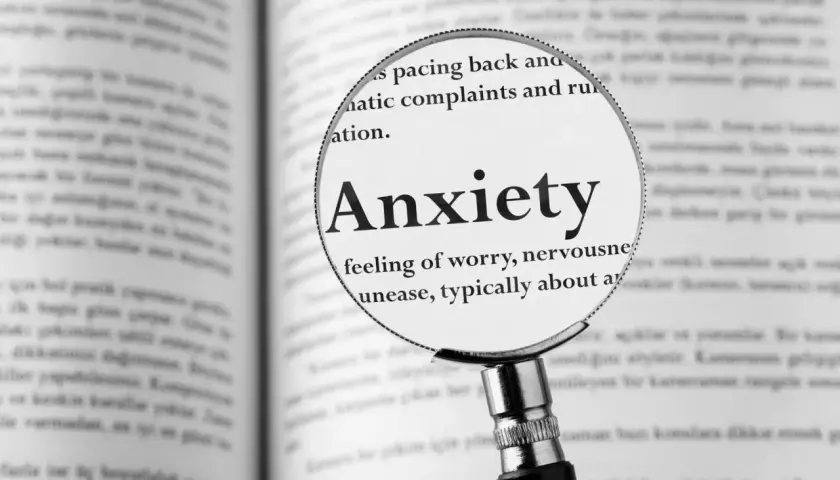 Lupa powiększa hasło "Anxiety" w książce, opisując uczucie niepokoju, które może towarzyszyć fobiom.