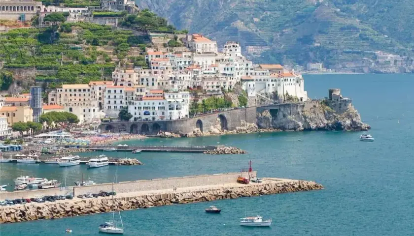 Amalfi: cosa vedere in un giorno. La pittoresca cittadina si affaccia sul mare blu, con case bianche aggrappate alla collina e un porto pieno di barche.