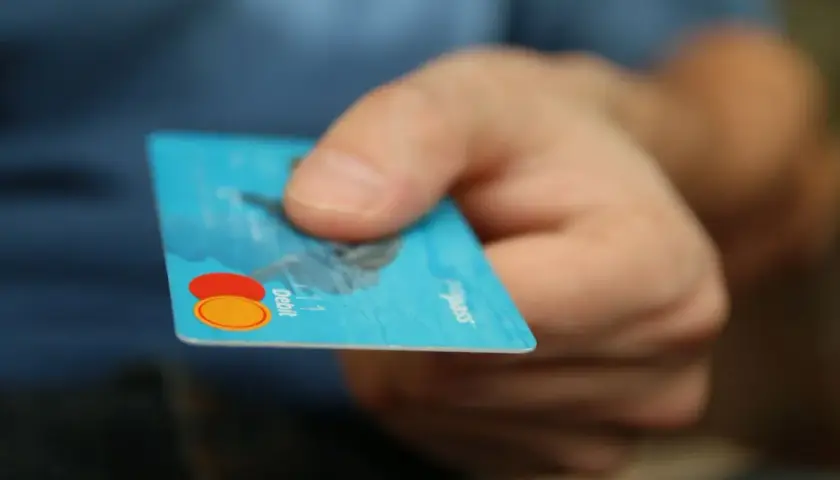 Main tenant une carte bancaire bleue, prêt à effectuer un achat. Il est possible de bloquer un paiement CB en cas de perte.