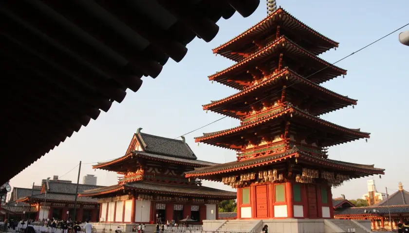 Pięciopiętrowa pagoda i inne budynki świątyni buddyjskiej w Japonii, z tradycyjnymi dachami i czerwonymi detalami.