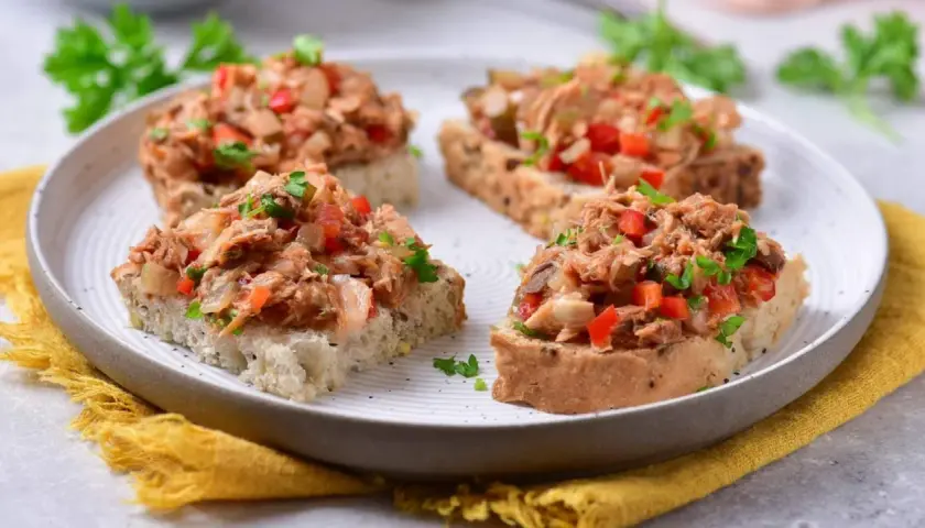 Chrupiące grzanki z makrelą w pomidorach, posypane natką pietruszki. Idealna przekąska na szybki lunch.