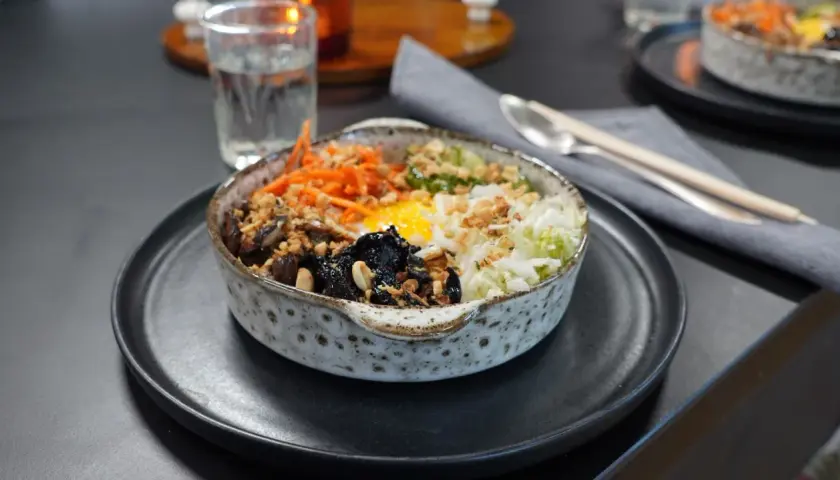 En vacker skål med bibimbap, fylld med ris, grönsaker, svamp och ett stekt ägg. Perfekt för ett snabbt och gott bibimbap recept.