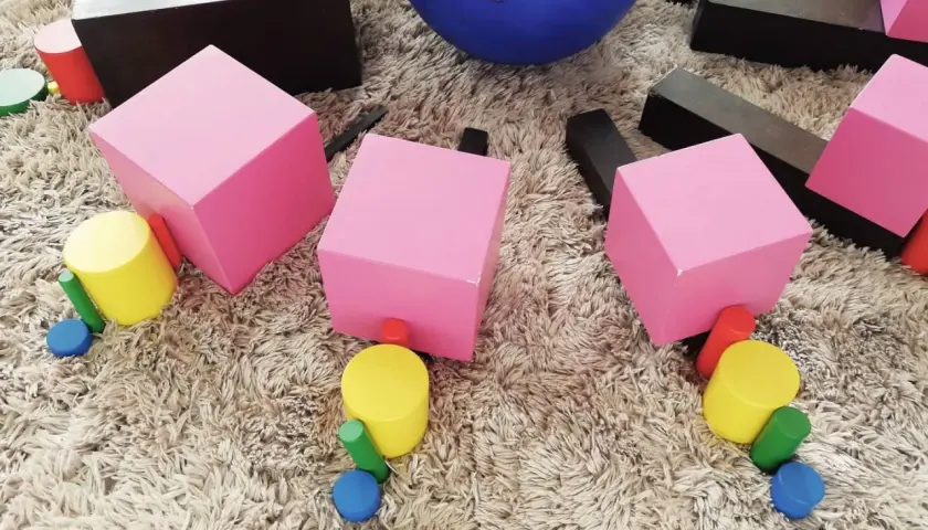 Kolorowe klocki i walce zachęcają do kreatywnych zabaw montessori dla 2 latka.