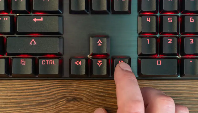 Palec naciska klawisz "Home" na podświetlanej klawiaturze programisty, co może być częścią skrótu klawiszowego.