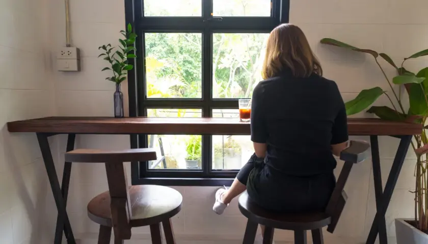 Kobieta siedzi przy oknie z napojem. Denerwuje mnie obecność męża, więc szukam chwili spokoju.
