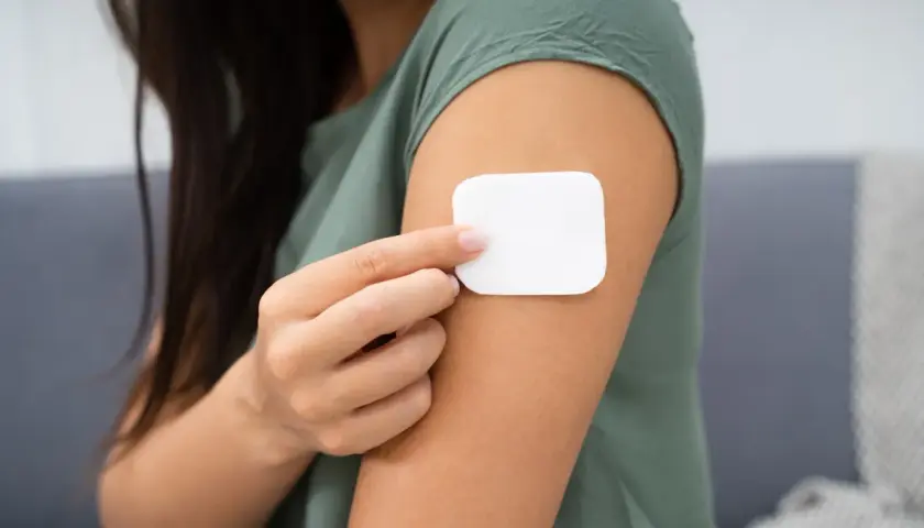 Kobieta przykleja plaster antykoncepcyjny. Przed użyciem warto zapoznać się z przeciwwskazaniami.