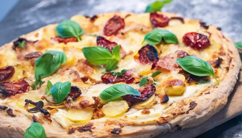 Leckeres Pizza Bianca Rezept mit Kartoffeln, Tomaten und frischem Basilikum.