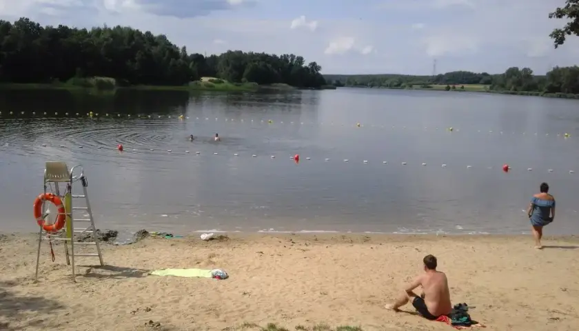 Słoneczny dzień nad zalewem Rybnik. Kąpielisko z ratownikiem, piaszczysta plaża i ludzie kąpiący się w wodzie.