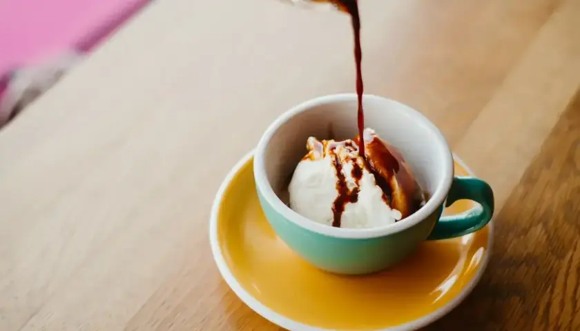 Gorące espresso zalewa kulkę lodów waniliowych w filiżance. Klasyczne lody po włosku, idealne na deser.