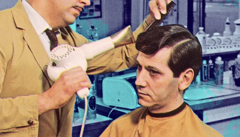 Coiffeur utilisant un sèche-cheveux pour **retendre du cuir** sur la coiffure d'un client.