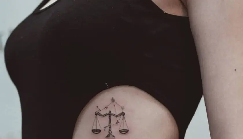 Delikatny tatuaż waga znak zodiaku na boku, ozdobiony gwiazdami.