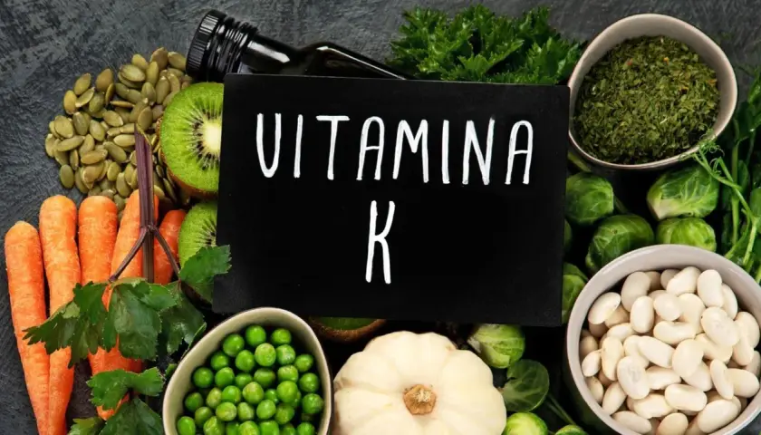 Variedad de alimentos ricos en vitamina K2: zanahorias, kiwi, semillas de calabaza, guisantes, coles de Bruselas, judías blancas y hierbas.