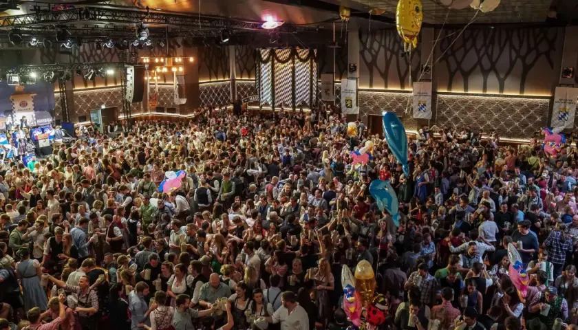 Volles Festzelt am Nockherberg 2026 mit vielen Menschen in Tracht, die Bierkrüge schwenken. Luftballons steigen auf.