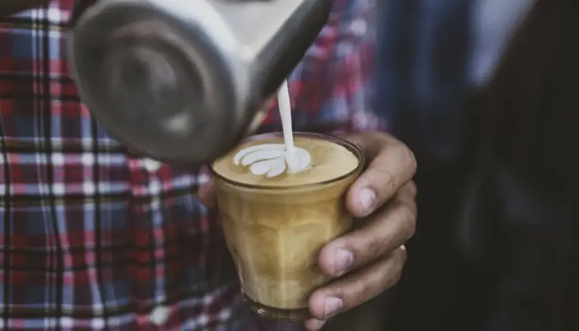 Barista wylewa mleko z dzbanka, tworząc wzór na kawie. To właśnie zabielacz do kawy, który nadaje jej kremową konsystencję i piękny wygląd.
