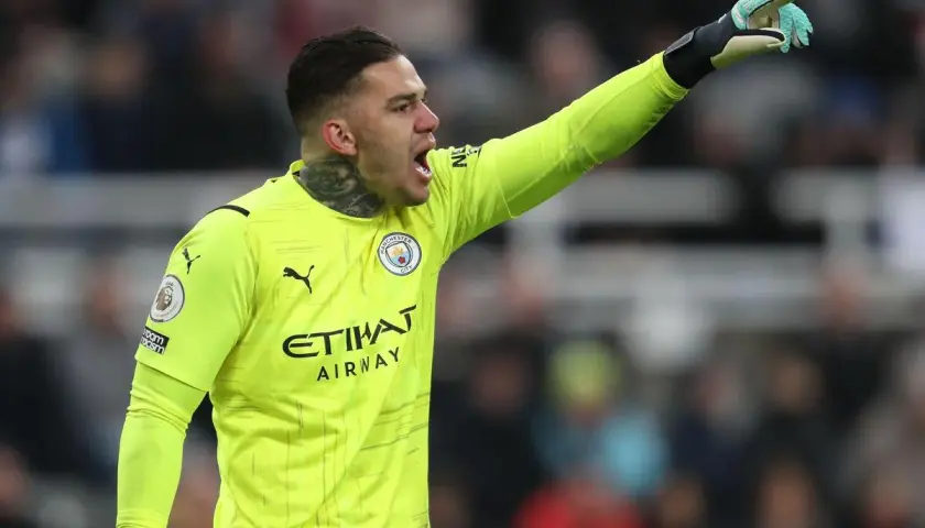 Bramkarz Manchester City w żółtej koszulce, z podniesioną ręką, gotowy do akcji. Skład Manchester City.