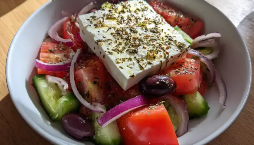 En fräsch grekisk sallad med fetaost, tomater, gurka, rödlök och oliver, toppad med örter.