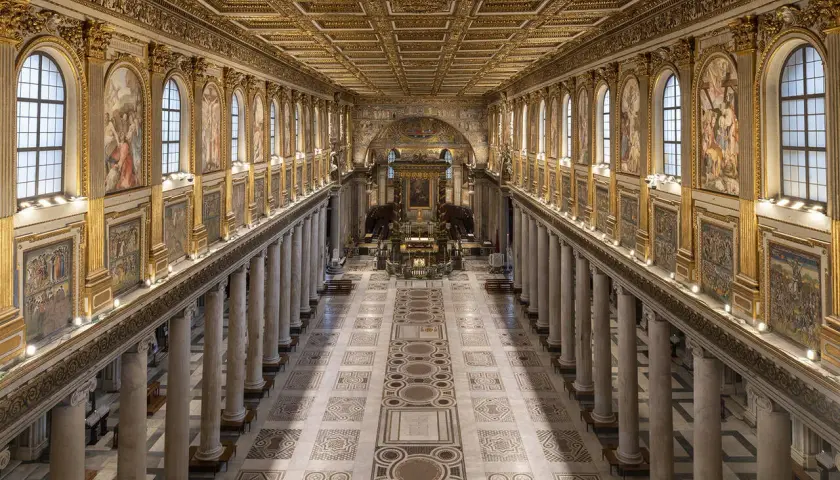 L'interno della Basilica di Santa Maria Maggiore a Roma, con il suo soffitto dorato, le colonne imponenti e i mosaici che narrano storie sacre.
