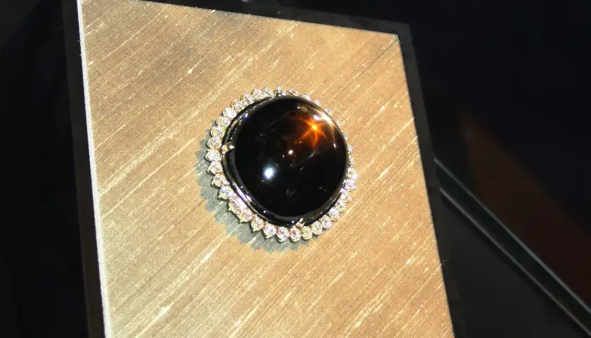 Ein glänzender schwarzer Saphir mit einem Stern-Effekt, umgeben von kleinen Diamanten. Seine geheimnisvolle schwarzer saphir bedeutung fasziniert.
