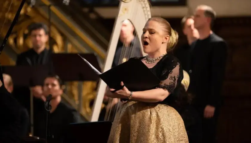 Sångerska med gyllene kjol framför en harpa under Stockholm Early Music Festival.
