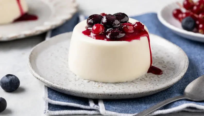 Panna cotta bianca con topping di frutti di bosco e salsa rossa. Ingredienti panna cotta freschi e invitanti.