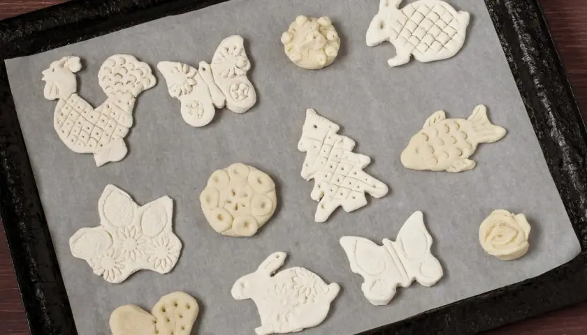 Figurki z masy solnej: kogut, motyl, królik, choinka, ryba, serce i kwiaty czekają na pieczenie.