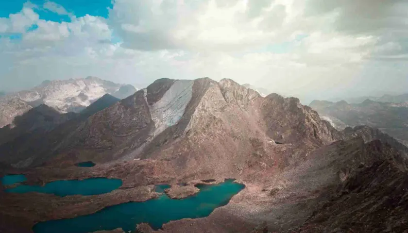 Paisaje montañoso con lagos turquesa, como si fueran los picos del infierno. Nubes blancas y cielo azul.