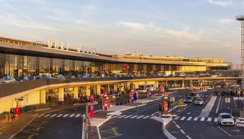 Orly Ouest, jedno z lotnisk w Paryżu, tętni życiem. Samochody, autobusy i pasażerowie tworzą dynamiczny obraz.