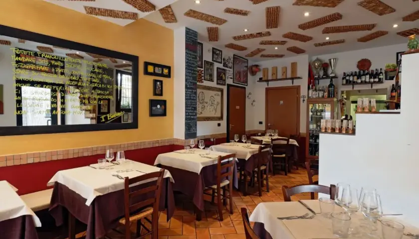 Interno di un'accogliente osteria a Bologna, con tavoli apparecchiati e un soffitto decorato con tappi di sughero.