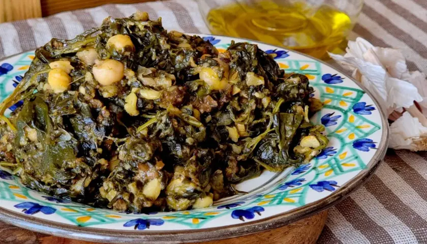Un plato de garbanzos con espinacas, cocinado con ajo y aceite de oliva.