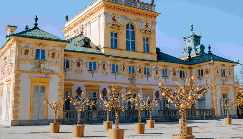 Barokowy pałac, jeden z pięknych muzeów w Polsce, z ozdobnymi drzewkami w donicach przed fasadą.