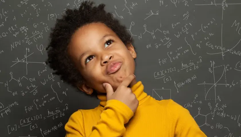 Un niño pensativo con un suéter amarillo, rodeado de fórmulas matemáticas y químicas en una pizarra, como si estuviera en el colegio.