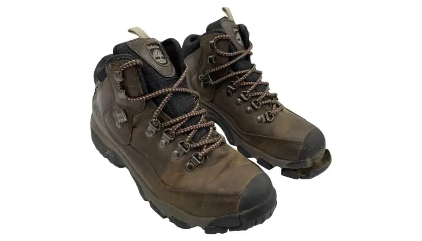 Well-worn brown hiking boots, one with the sole coming off, showing signs of many adventures.