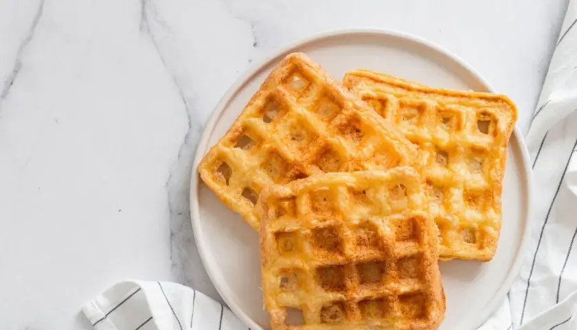 Trois gaufres au sarrasin dorées et croustillantes sur une assiette blanche, prêtes à être dégustées.