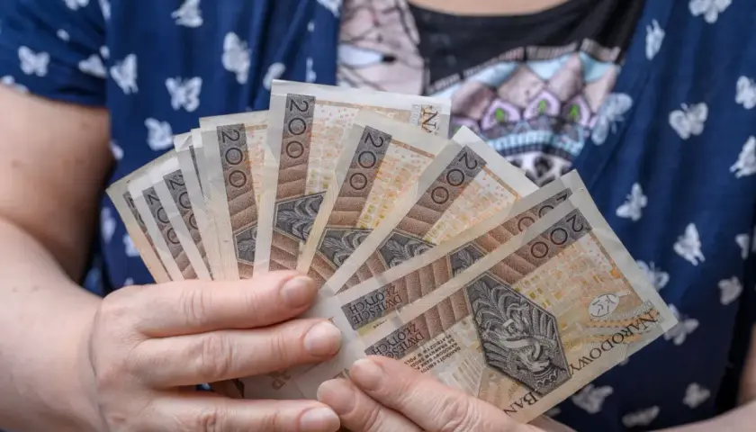 Dłonie trzymające kilka banknotów po 200 zł. Czy to przyszłość renty wdowiej? Zmiany w przepisach mogą wpłynąć na finanse.