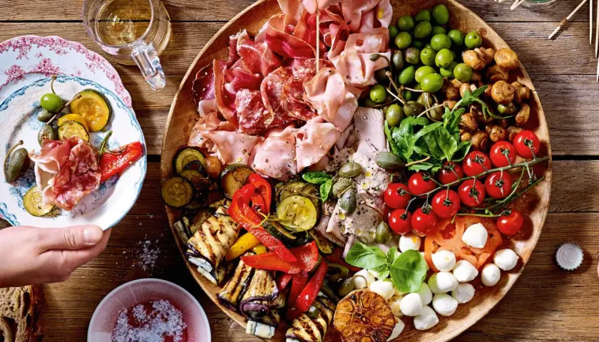 Eine üppige antipasti platte mit Wurst, Käse, Oliven, gegrilltem Gemüse und Tomaten.