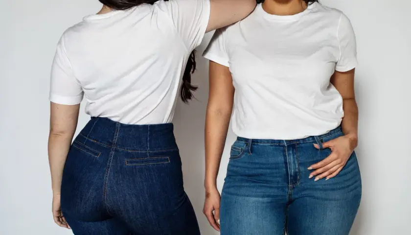 Dwie kobiety w białych T-shirtach i jeansach. Wysoki stan spodni to świetny sposób, jak ukryć brzuch w spodniach.
