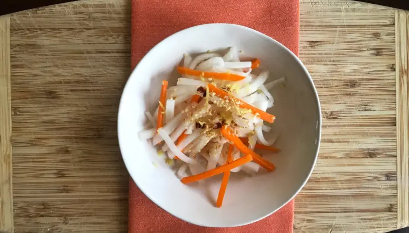 A refreshing namasu recipe with julienned daikon radish and carrots, seasoned with sesame seeds and a hint of citrus zest.