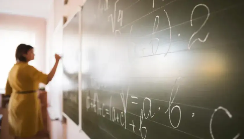 Nauczycielka pisze wzory matematyczne na tablicy. To jak art 20 kn, gdzie każdy symbol ma swoje znaczenie.