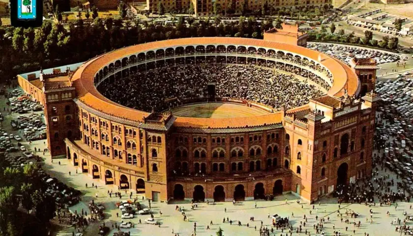 Vista aérea de la plaza de toros Las Ventas, llena de espectadores, con coches aparcados alrededor y gente paseando.