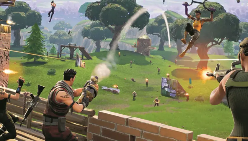 Gracze Fortnite, stworzonego przez Epic Games, walczą na zielonej wyspie. Jedna postać spada na spadochronie, inni strzelają.