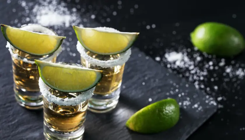 Kieliszki tequili z solą i limonką. Idealne dodatki, by wiedzieć, z czym pić tequilę.