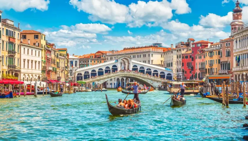 Gondole płynące po Canale Grande w Wenecji, z widokiem na Most Rialto i kolorowe kamienice. Ten region to kwintesencja włoskiego piękna.