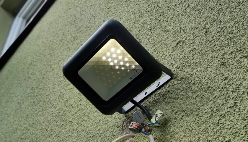 Nowa lampa led żarzy się po włączeniu, oświetlając zieloną ścianę.
