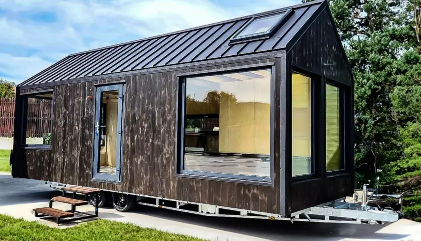 Nowoczesny tiny house w Polsce, z ciemną drewnianą elewacją i dużymi oknami, gotowy na przygodę.