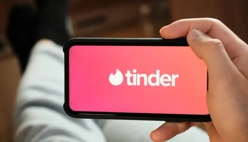 Dłoń trzyma smartfon z logo Tindera. Szukasz alternatywy dla Tindera? Może warto spróbować czegoś nowego.