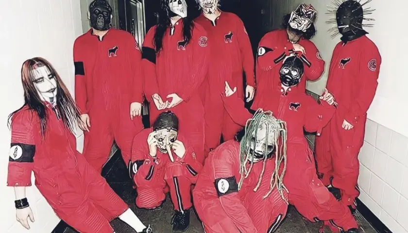 Zespół Slipknot w czerwonych kombinezonach i charakterystycznych maskach, pozuje do zdjęcia w korytarzu.